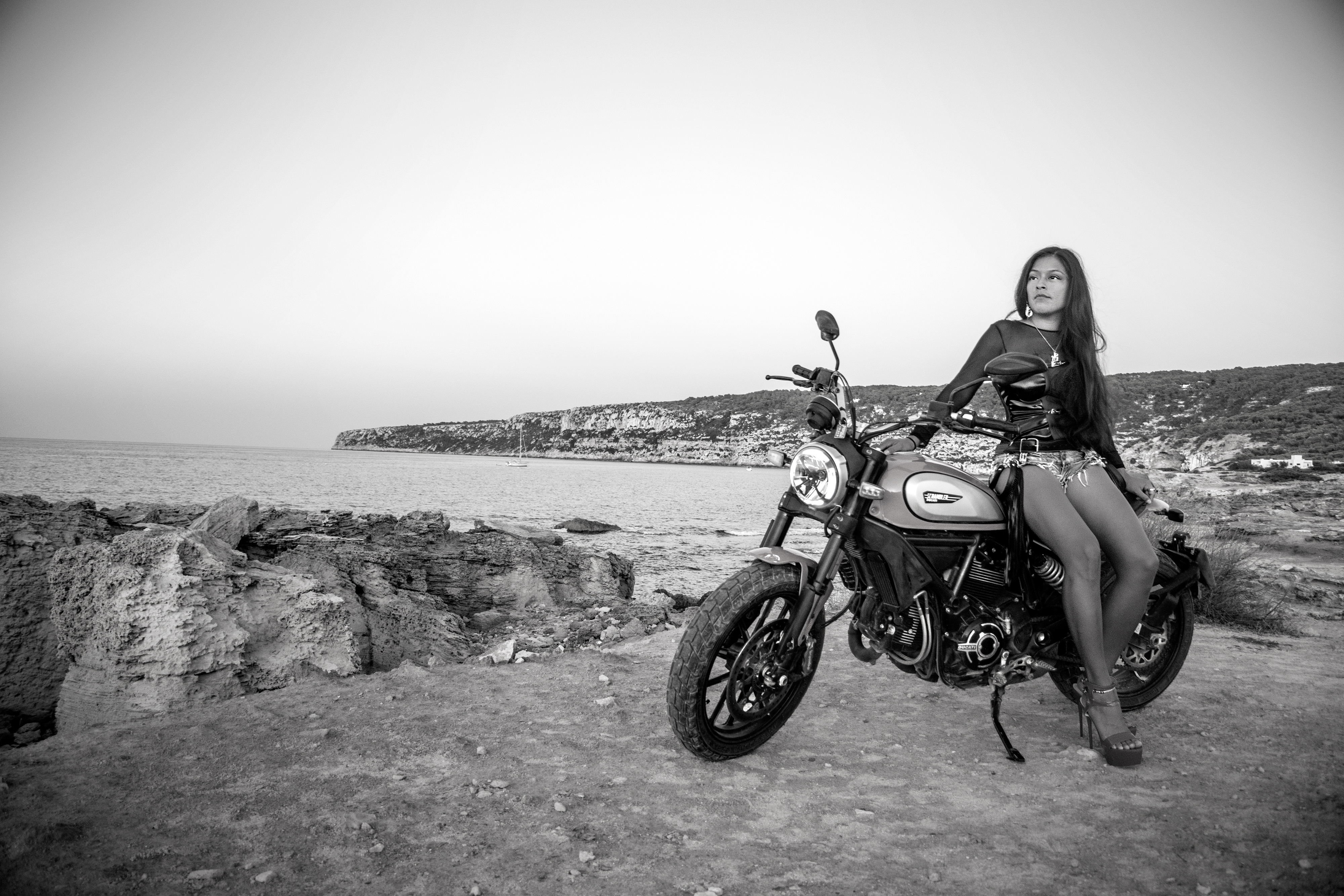 Black and white photography of a sexy girl wearing high heels with a motorcycle at Es Calo beach, Formentera, Spain, (Nos Dren)