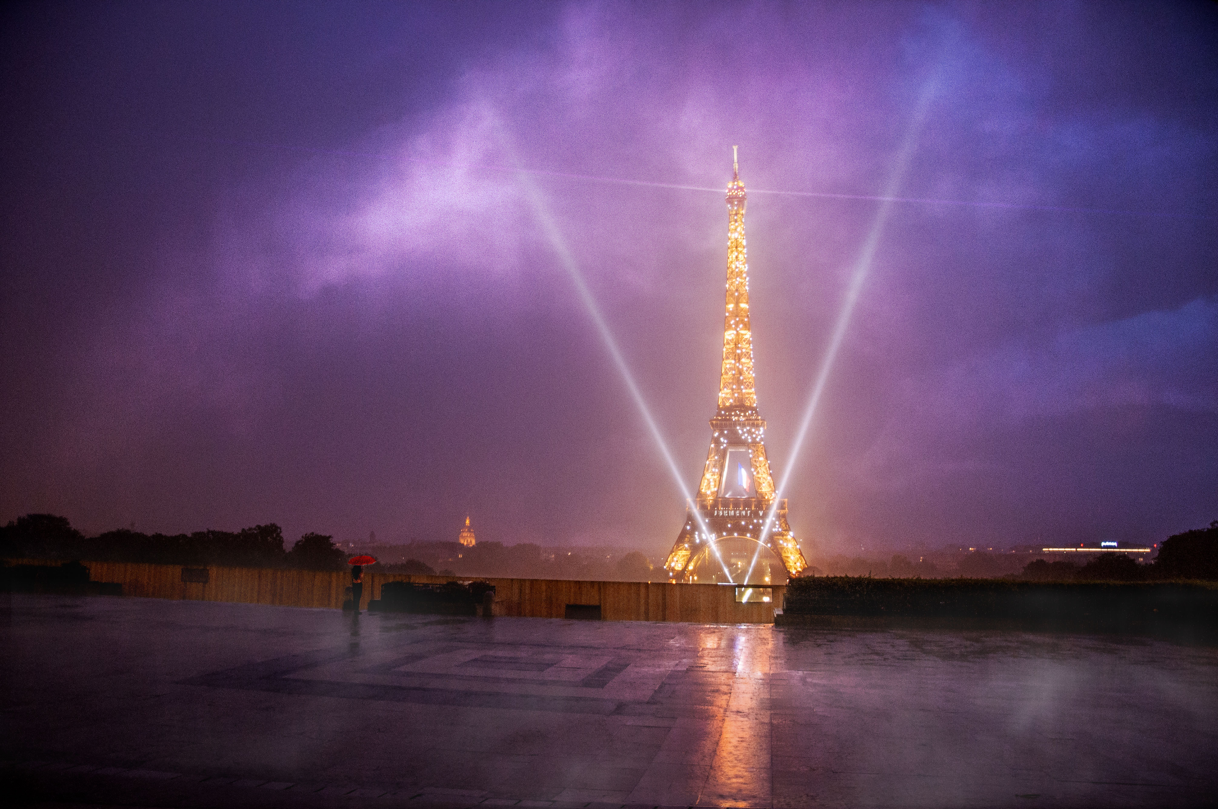 Paris Eiffel Tower view from Trocadero under storm, cloud dans heavy rain with a girl with a red umbrella. The Tour Eiffel is lit especially to thanks medical staff due to coronavirus COVID-19 2020, (Nos Dren).